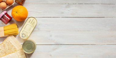 Ahşap arka planda bağışlanan yiyeceklerin fotokopisi. Modifiye et. Pirinç, konserve, yulaf gevreği, yumurta, reçel, pasta. Karantina sırasında gıda bağışları veya yemek dağıtım hizmeti kavramı.