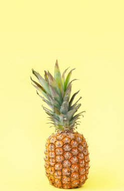 Sarı arka planda tam bir ananas. Konsept: yaz, yemek, yaratıcı düzen. Yakın plan. Uzayı metin için kopyala. Dikey