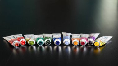 Profesyonel suluboya, arka planda koyu bulanık tüpler içinde. Ressam için renkli bir palet. Seçici odaklanma. Uzayı metin için kopyala. Yakın plan.