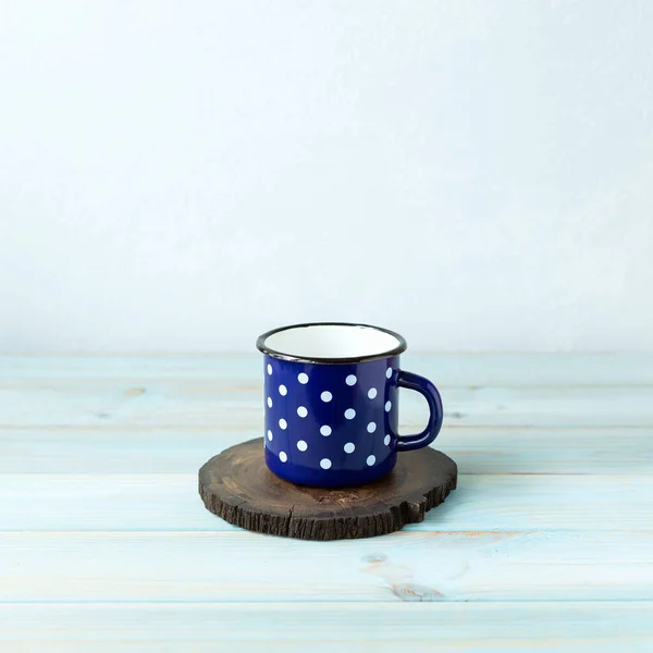 Dark blue mug  polka dots for drinks on a wooden stand. Background with copy space.Close up. Square