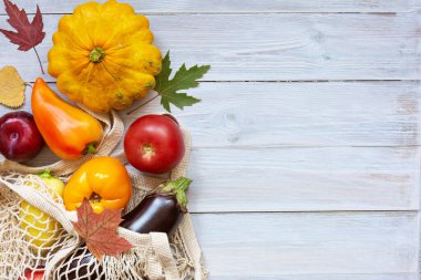 Tahta arka planda mevsimlik meyve ve sebzelerle birlikte çevre dostu ip torbası. Konsept: Çevre alışverişi, sıfır atık, hasat festivali. Sonbahar havası. Düz alan. Metnin için alanı kopyala.