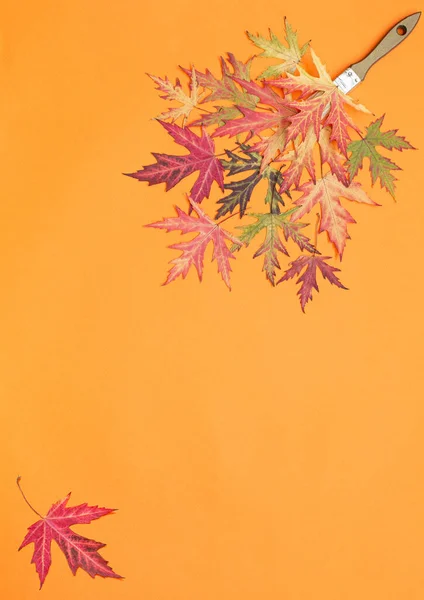 Autumn template multi colored maple leaves on orange background. Concept: autumn  paints, fall sales, holidays. Vertical.  Flat lay. Copy space for text.