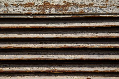 Paslı metal ızgaralar, boyayla boyanmış ve yaşlılıktan soyulmuş, endüstriyel tesislere hava girişi için havalandırma delikleri, bir elektrikli kalkan, bir açık kapı.