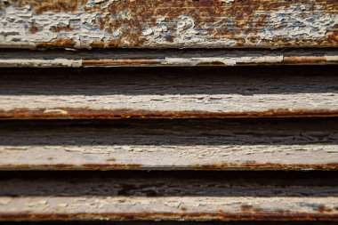 Paslı metal ızgaralar, boyayla boyanmış ve yaşlılıktan soyulmuş, endüstriyel tesislere hava girişi için havalandırma delikleri, bir elektrikli kalkan, bir açık kapı.