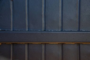 Paslı metal ızgaralar, boyayla boyanmış ve yaşlılıktan soyulmuş, endüstriyel tesislere hava girişi için havalandırma delikleri, bir elektrikli kalkan, bir açık kapı.