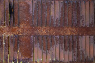 Paslı metal ızgaralar, boyayla boyanmış ve yaşlılıktan soyulmuş, endüstriyel tesislere hava girişi için havalandırma delikleri, bir elektrikli kalkan, bir açık kapı.