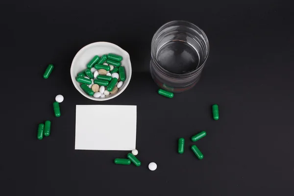 Pastillas con vaso de agua para beber las pastillas sobre fondo negro oscuro. Dolor. — Foto de Stock