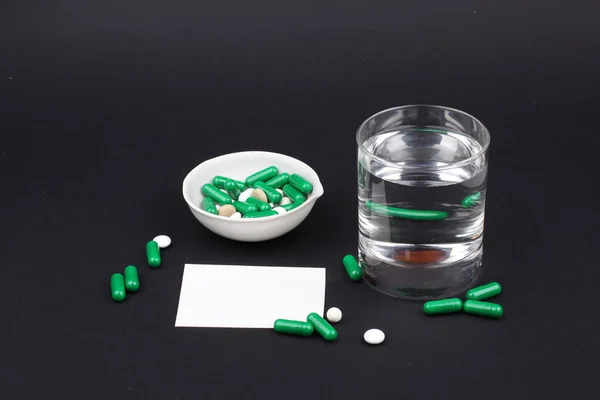 Pílulas com vidro de água para beber as pílulas em fundo preto escuro. Dor — Fotografia de Stock