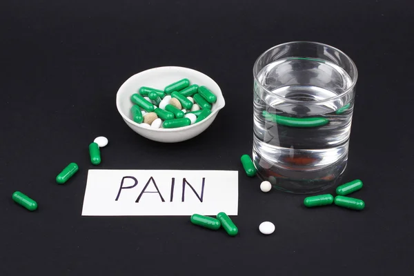 pills with glass of water to drink the pills on dark black background. Pain