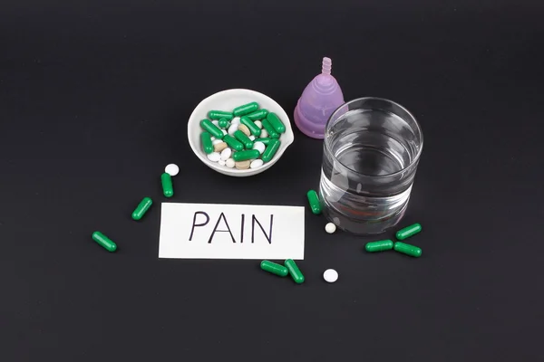 Productos de higiene femenina con pastillas y agua de vidrio sobre fondo negro — Foto de Stock
