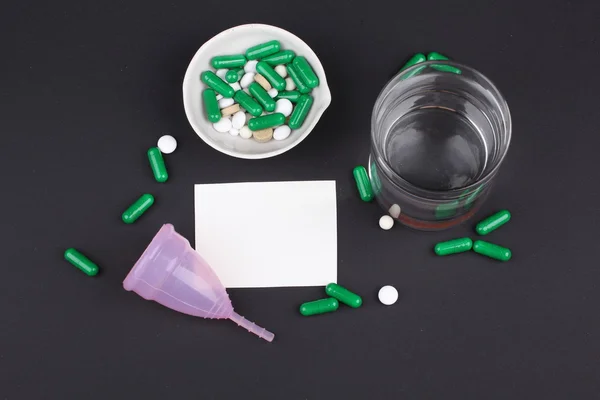 Productos de higiene femenina con pastillas y agua de vidrio sobre fondo negro — Foto de Stock