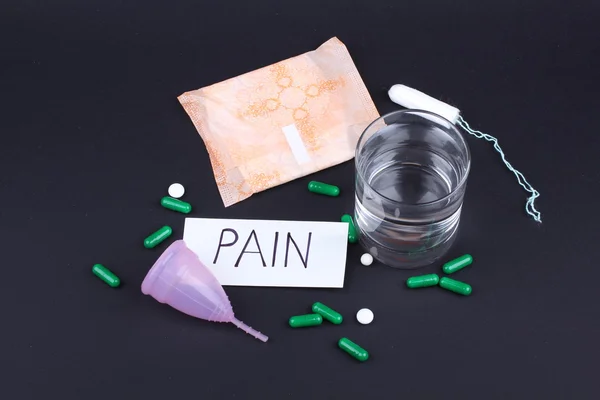 Productos de higiene femenina con pastillas y agua de vidrio sobre fondo negro — Foto de Stock