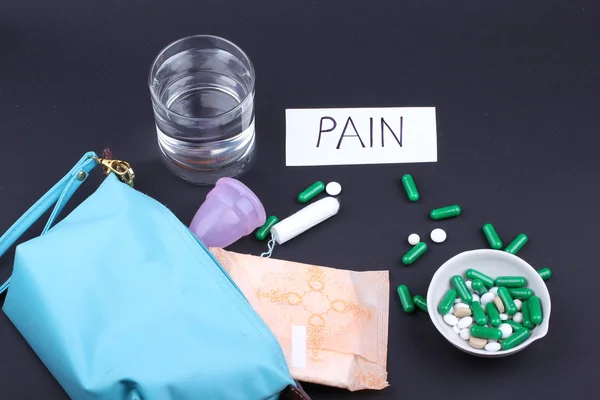 Productos de higiene femenina con pastillas y agua de vidrio sobre fondo negro — Foto de Stock