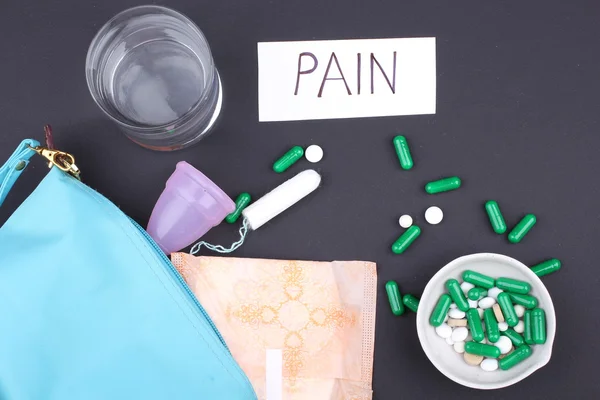 Productos de higiene femenina con pastillas y agua de vidrio sobre fondo negro — Foto de Stock