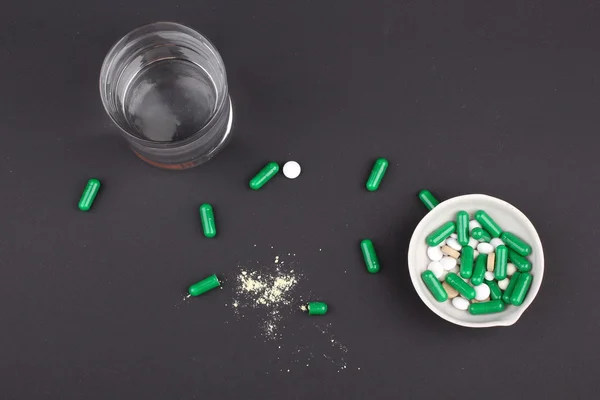 Pílulas com vidro de água para beber as pílulas em fundo preto escuro. Dor — Fotografia de Stock