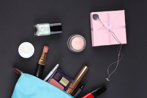 Hermosa bolsa de maquillaje con cosméticos sobre fondo negro —  Fotos de Stock