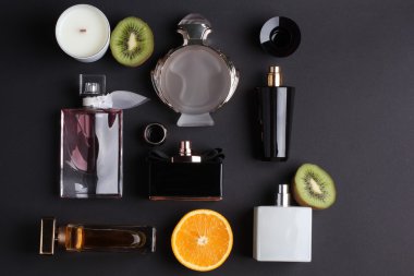 siyah arka plan üzerine meyve ile farklı parfüm şişeleri