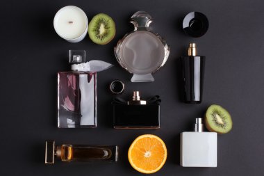 siyah arka plan üzerine meyve ile farklı parfüm şişeleri