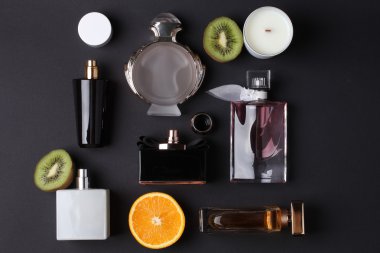siyah arka plan üzerine meyve ile farklı parfüm şişeleri