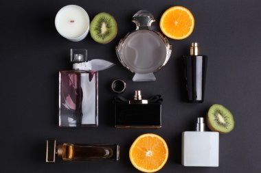 siyah arka plan üzerine meyve ile farklı parfüm şişeleri