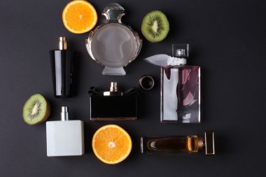 siyah arka plan üzerine meyve ile farklı parfüm şişeleri