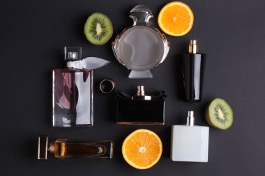 siyah arka plan üzerine meyve ile farklı parfüm şişeleri