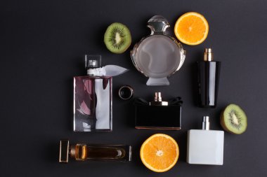 siyah arka plan üzerine meyve ile farklı parfüm şişeleri