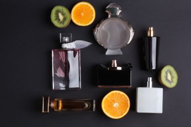 siyah arka plan üzerine meyve ile farklı parfüm şişeleri