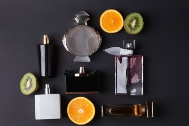 siyah arka plan üzerine meyve ile farklı parfüm şişeleri