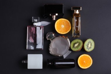 siyah arka plan üzerine meyve ile farklı parfüm şişeleri