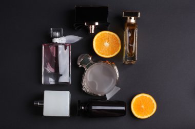 siyah arka plan üzerine meyve ile farklı parfüm şişeleri