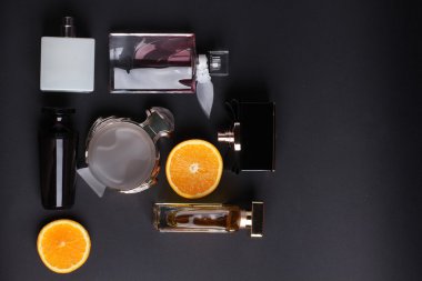 siyah arka plan üzerine meyve ile farklı parfüm şişeleri