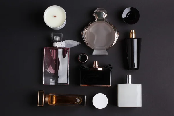 Diferentes botellas de perfume sobre fondo negro — Foto de Stock