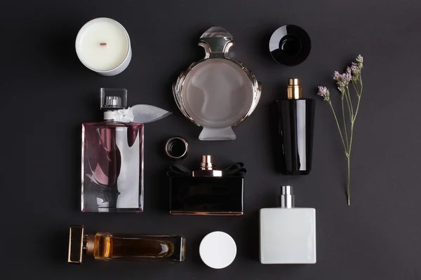 Diferentes botellas de perfume sobre fondo negro — Foto de Stock
