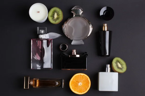 Diverse bottiglie di profumo con frutta su sfondo nero — Foto Stock
