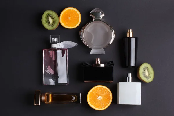Diferentes frascos de perfume con fruta sobre fondo negro — Foto de Stock