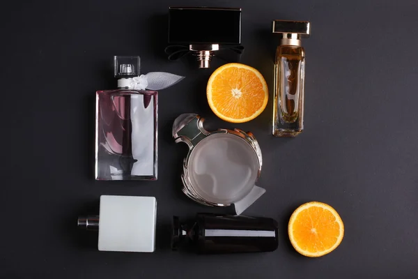 Diferentes frascos de perfume con fruta sobre fondo negro — Foto de Stock