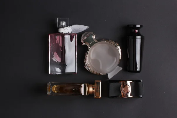 Diferentes botellas de perfume sobre fondo negro — Foto de Stock