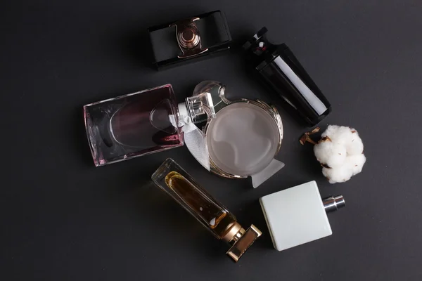 Diferentes botellas de perfume sobre fondo negro — Foto de Stock