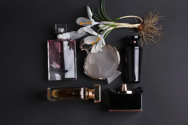 Perfume bottles surrounded by flower on black background. — Stock Photo, Image