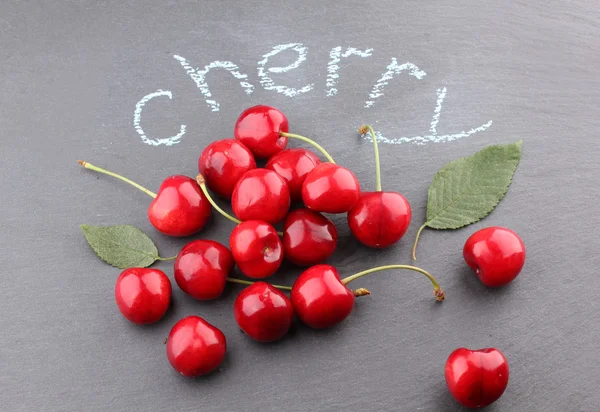 Fresh cherries on black chalkboard — Stock Photo, Image