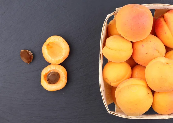 Абрикосы. Группа собранных абрикосов на корзине, вид сверху, фон на доске . — стоковое фото