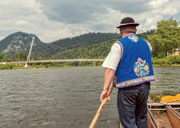 Рафтсман сплавляет туристов по реке Дунаец на юге Польши. T
