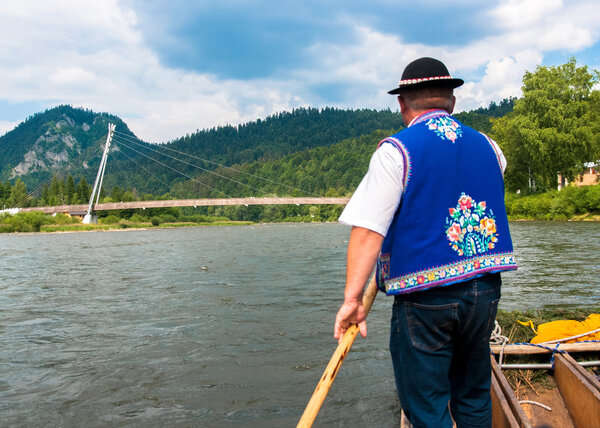 Рафтсман сплавляет туристов по реке Дунаец на юге Польши. T
