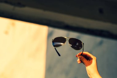 Havacı güneş gözlüğü modeli. Erkekler için büyük siyah lensleri var. Bir yaz gününde el ele tutuşuyorlar. Seçici odak