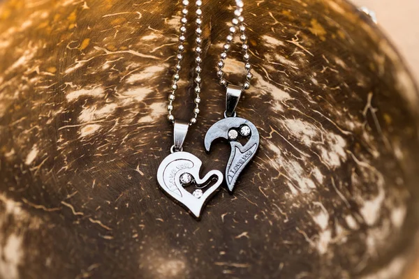 Couple set pendant necklace half of heart shoot outdoors in a sunny day closeup. Selective focus
