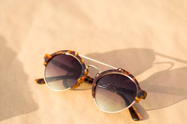 Güneşli bir günde yuvarlak lensli klasik güneş gözlüğü modeli dışarıda çekim yapıyor. Seçici odak