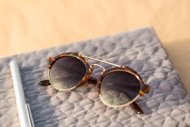 Güneşli bir günde yuvarlak lensli klasik güneş gözlüğü modeli dışarıda çekim yapıyor. Seçici odak