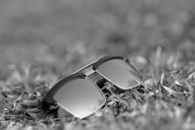 Güneşli bir günde çimlerin üzerinde gümüş lensli klasik güneş gözlüğü modeli çekiliyor. Seçici odak