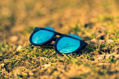 Özel tasarımı olan bayanlar için büyük mavi lensleri olan güneş gözlüklü özel bir model doğada yakın çekim yapıyor. Seçici odak 